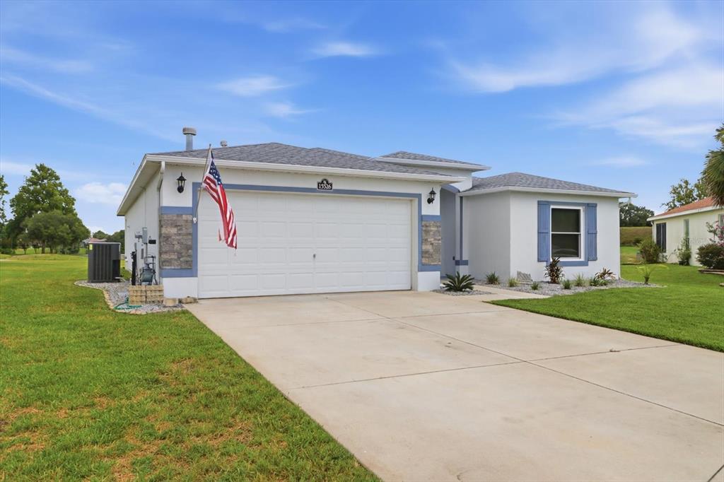 A single-story house with a white stucco exterior, stone accents, and a two-car garage — 15526 SW 11TH TERRACE ROAD, OCALA, FL
