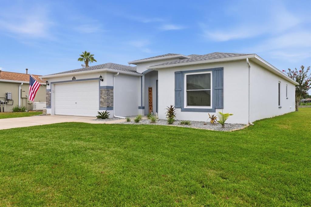 A single-story house with a white stucco exterior, blue shutters, and a two-car garage — 15526 SW 11TH TERRACE ROAD, OCALA, FL