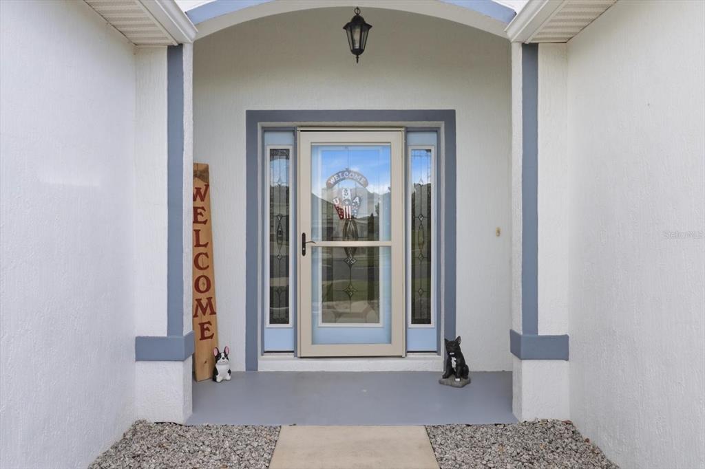 A front entryway features a light-colored storm door with sidelights, a welcome sign, and statues — 15526 SW 11TH TERRACE ROAD, OCALA, FL