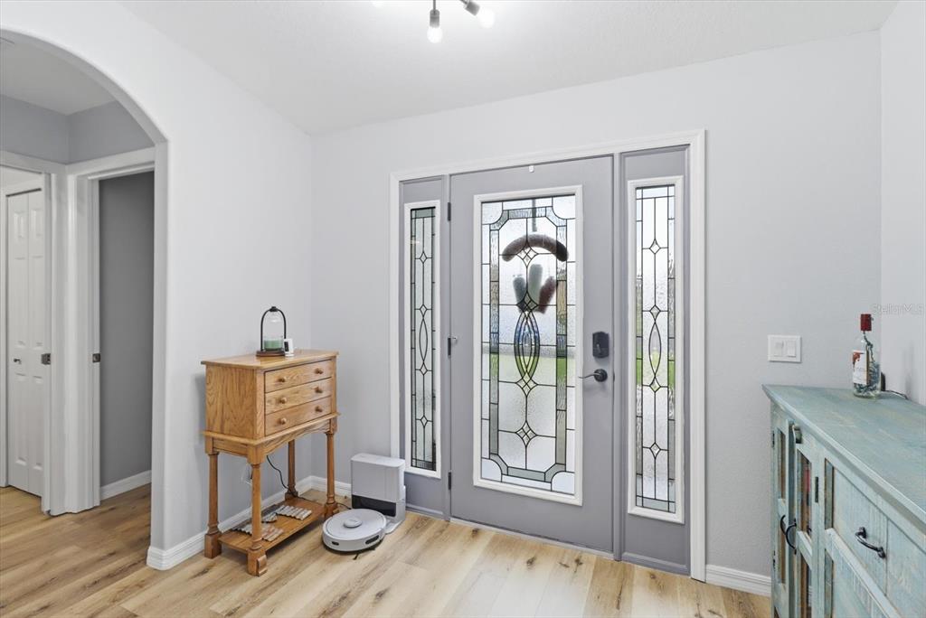 An entryway features light wood flooring, a gray front door with glass panels, and furniture — 15526 SW 11TH TERRACE ROAD, OCALA, FL