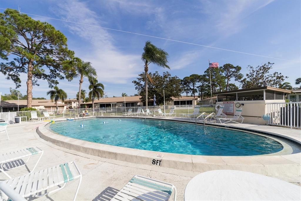 An outdoor swimming pool with lounge chairs and palm trees under a clear blue sky — 2809 SWIFTON DRIVE UNIT 4, SARASOTA, FL