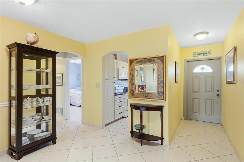 An entryway with yellow walls, tiled floors, a glass display cabinet, and a front door — 2809 SWIFTON DRIVE UNIT 4, SARASOTA, FL