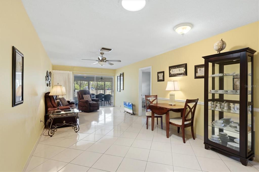 A living and dining room with yellow walls, tile floors, and a glass display cabinet — 2809 SWIFTON DRIVE UNIT 4, SARASOTA, FL