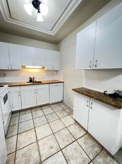 A kitchen with white cabinets, brown granite countertops, and light-colored tile flooring — 6289 Lear Drive # 302, Atlantis FL 33462, ATLANTIS, FL
