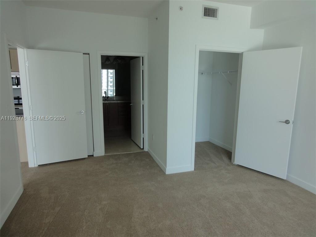 A carpeted bedroom features two white doors and an open closet — 79 SW 12th St # 1203S, Miami FL 33130, MIAMI, FL