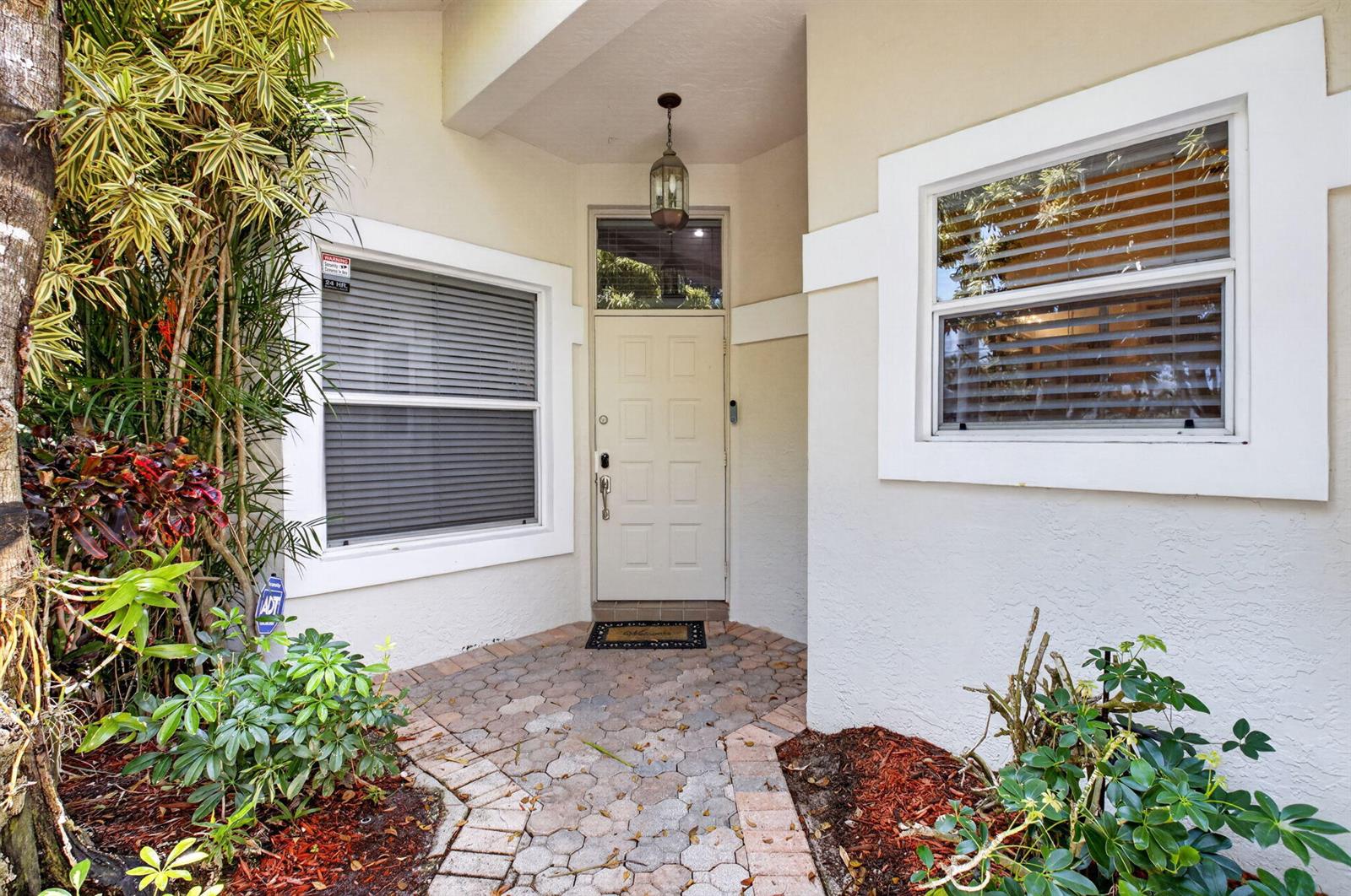 The front entrance features a white door, two windows with blinds, and a paved walkway — 6694 NW 26th Way, Boca Raton FL 33496, BOCA RATON, FL
