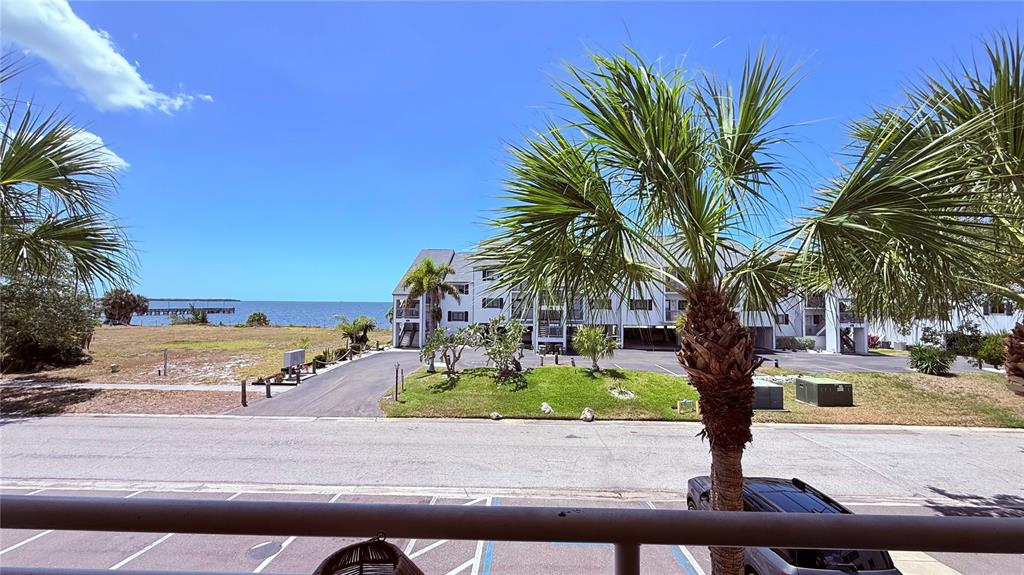 An elevated view of a parking lot, a palm tree, and a building near water — 611 DESTINY DRIVE UNIT 410, RUSKIN, FL