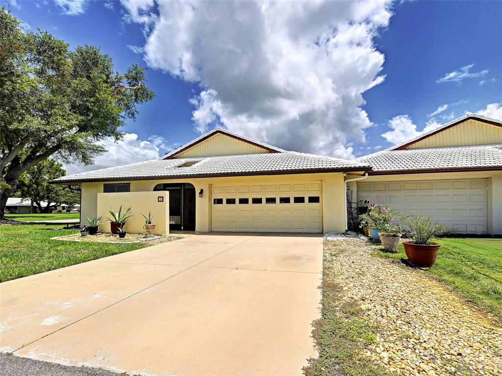 A single-story house with a two-car garage, a concrete driveway, and a light-colored tile roof — 20 IDLE SANDS DRIVE, VENICE, FL