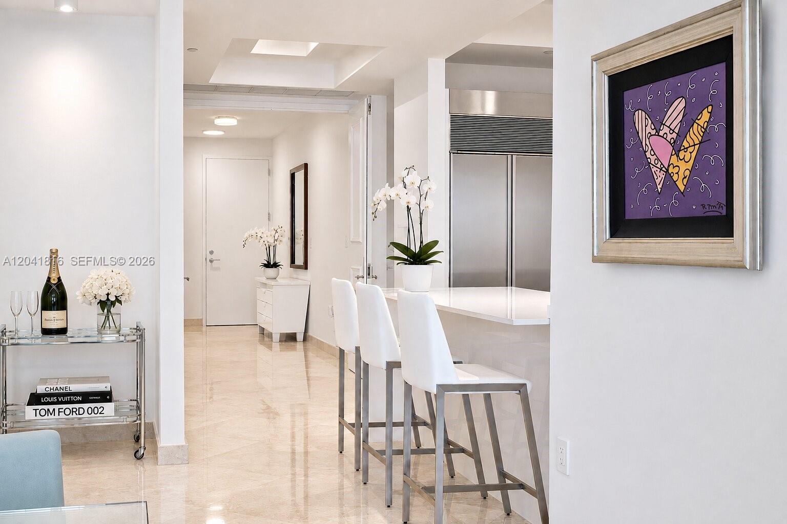 A bright hallway leads to a kitchen with a breakfast bar and white bar stools — 100 S Pointe Dr # 1507, Miami Beach FL 33139, MIAMI BEACH, FL