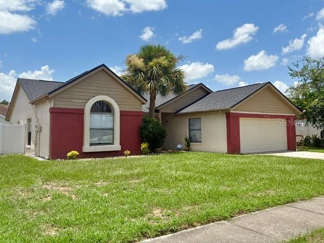 A single-story house features a tan exterior with red brick accents and a palm tree — 2224 FAIRMONT CIRCLE, ORLANDO, FL