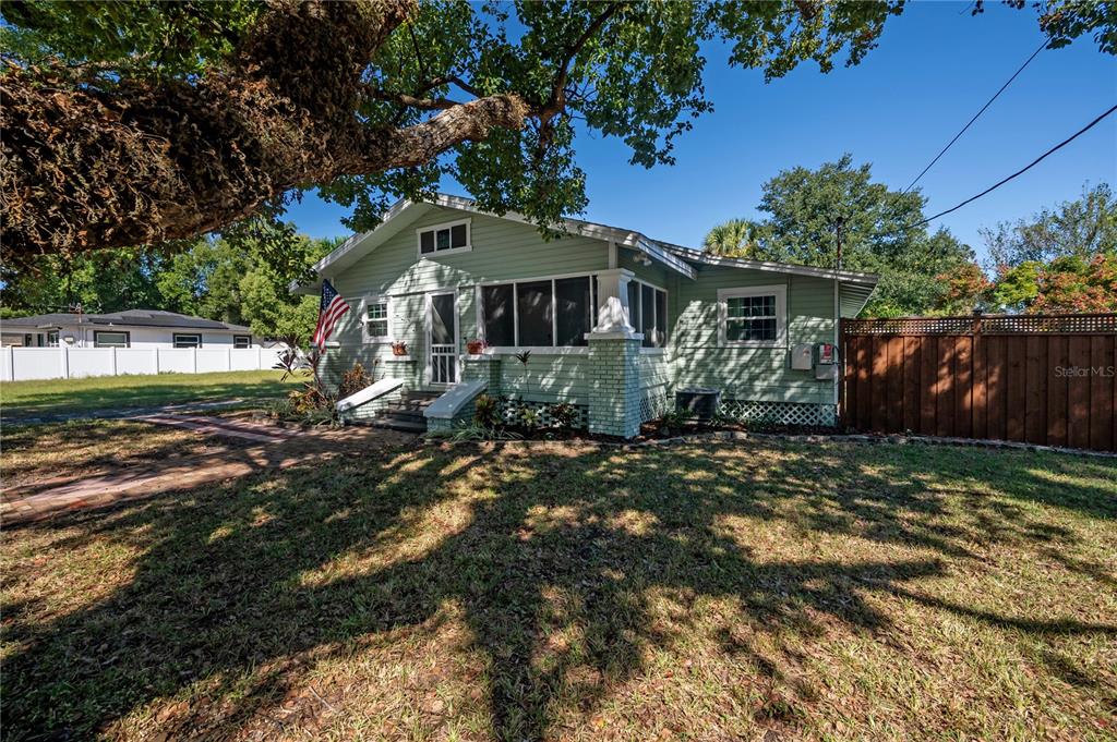 A light green, single-story house with a screened front porch and a wooden privacy fence — 1404 E CAYUGA STREET, TAMPA, FL