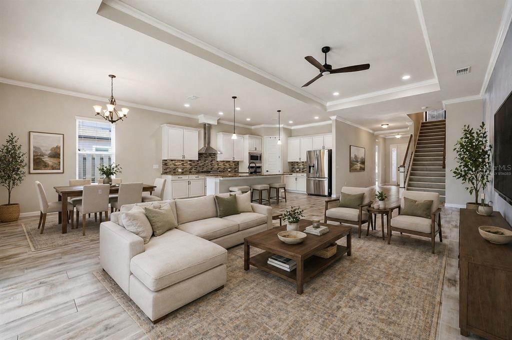 An open-concept living room, dining area, and kitchen feature light wood floors and neutral decor — 1061 NW 134TH DRIVE, NEWBERRY, FL