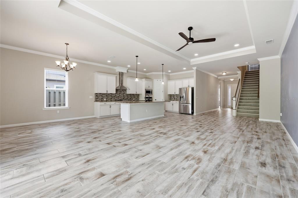 A spacious open-concept kitchen and living area features white cabinetry, an island, and wood-look flooring — 1061 NW 134TH DRIVE, NEWBERRY, FL