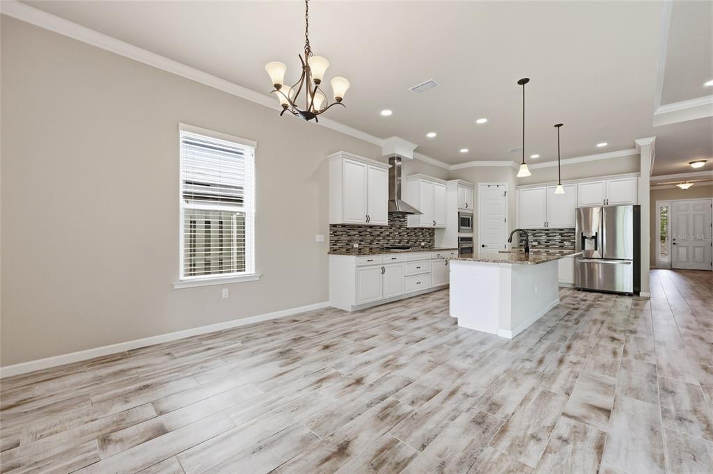 A kitchen and dining area feature white cabinets, a center island, and wood-look tile flooring — 1061 NW 134TH DRIVE, NEWBERRY, FL