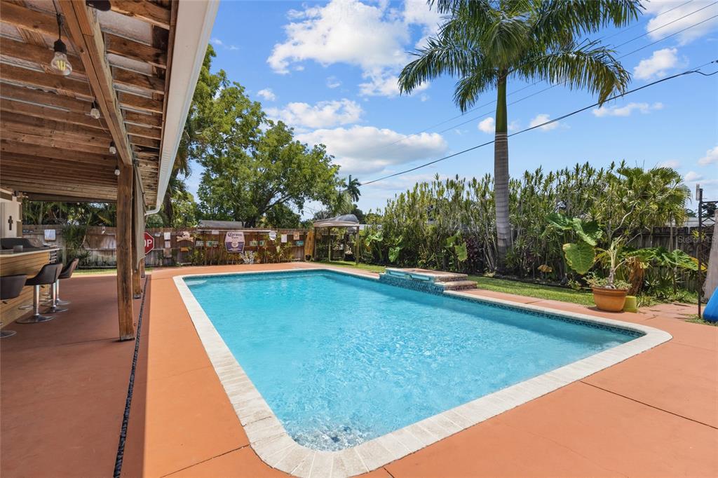 An outdoor swimming pool with a patio and a covered bar area under a wooden pergola — 311 62ND STREET W, BRADENTON, FL