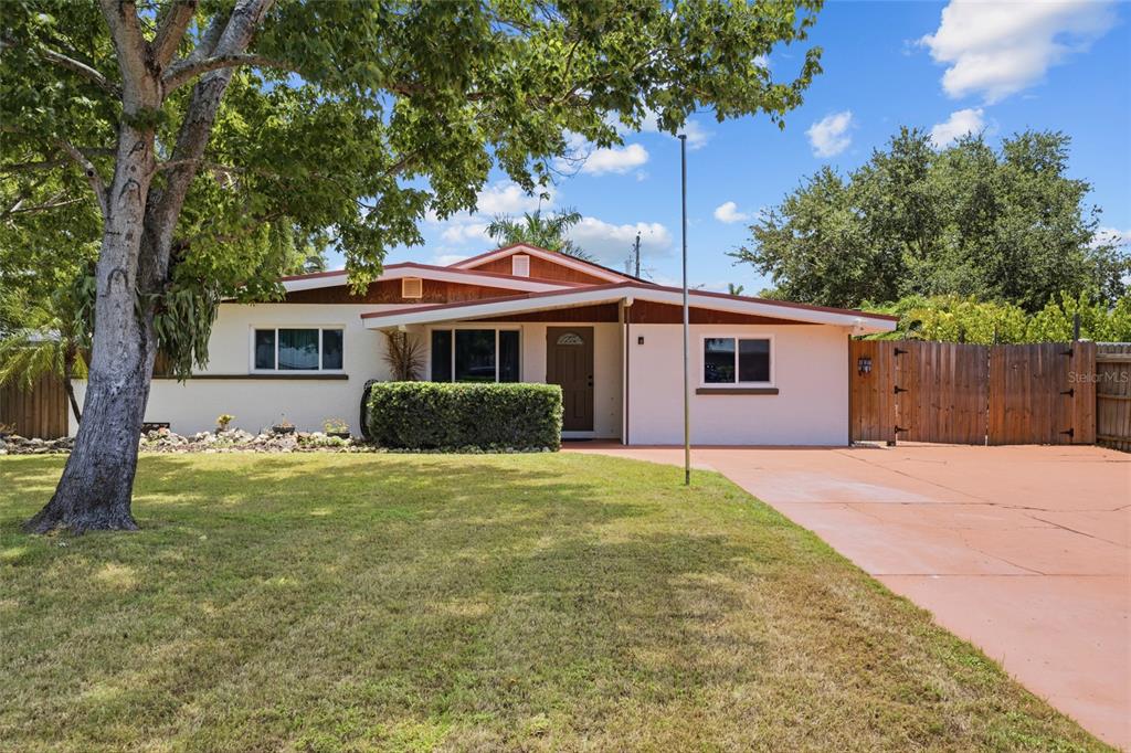 A single-story house with a white exterior, brown trim, a large tree, and a driveway — 311 62ND STREET W, BRADENTON, FL