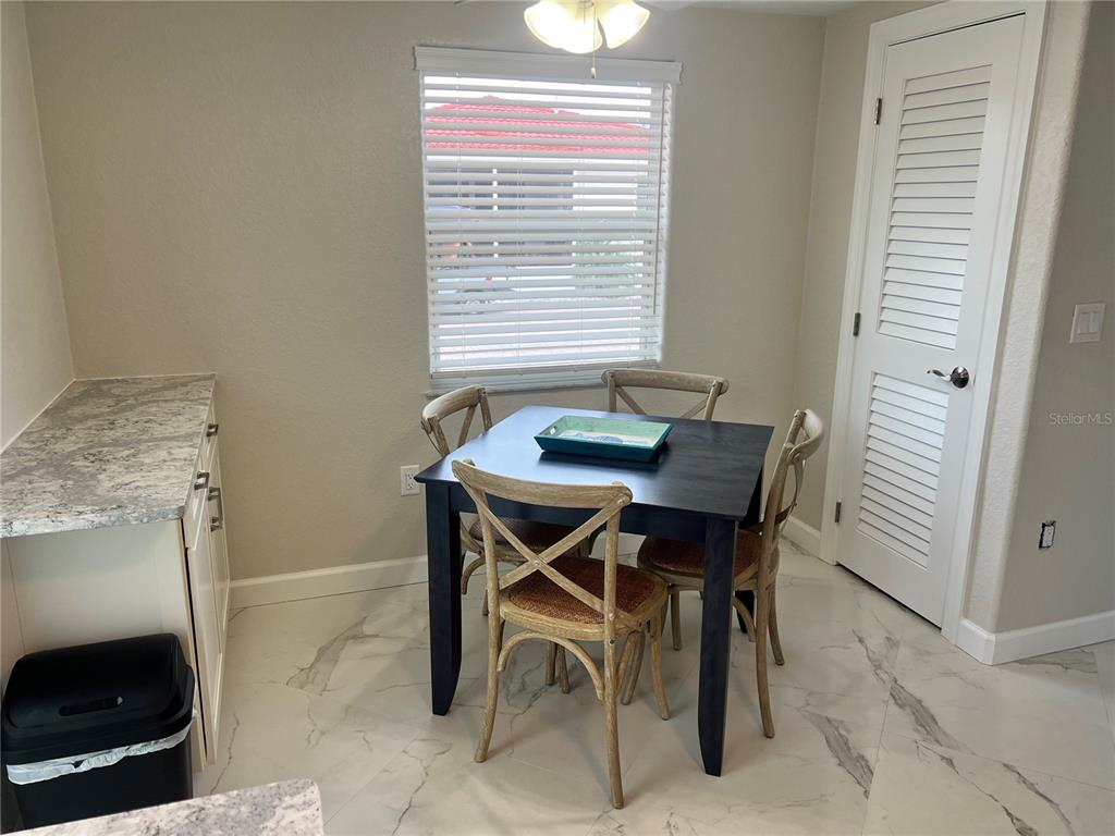 A dining area features a dark square table, four wooden chairs, and light tile flooring — 6154 MIDNIGHT PASS ROAD UNIT B14, SARASOTA, FL