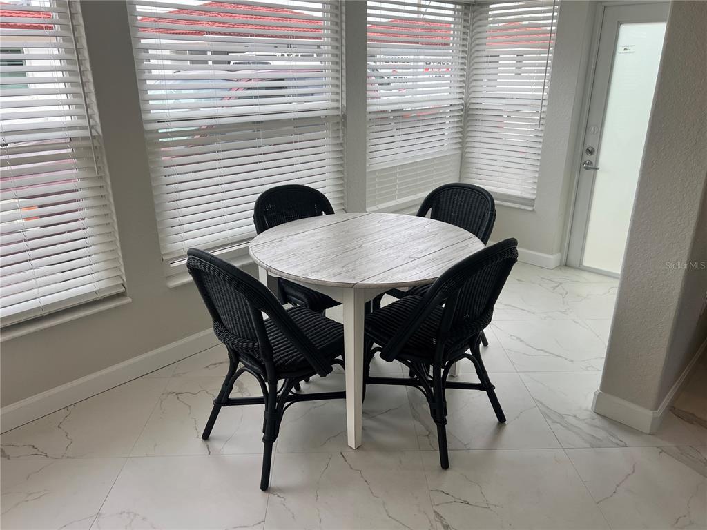 A dining area features a round table with four black wicker chairs on tiled floors — 6154 MIDNIGHT PASS ROAD UNIT B14, SARASOTA, FL