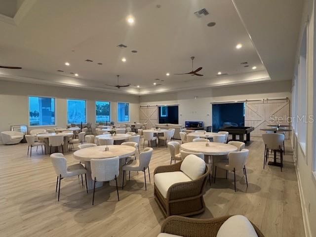 A spacious community room features multiple round dining tables, light wood flooring, and ceiling fans — 9001 GASPARILLA ROAD UNIT 22, PLACIDA, FL