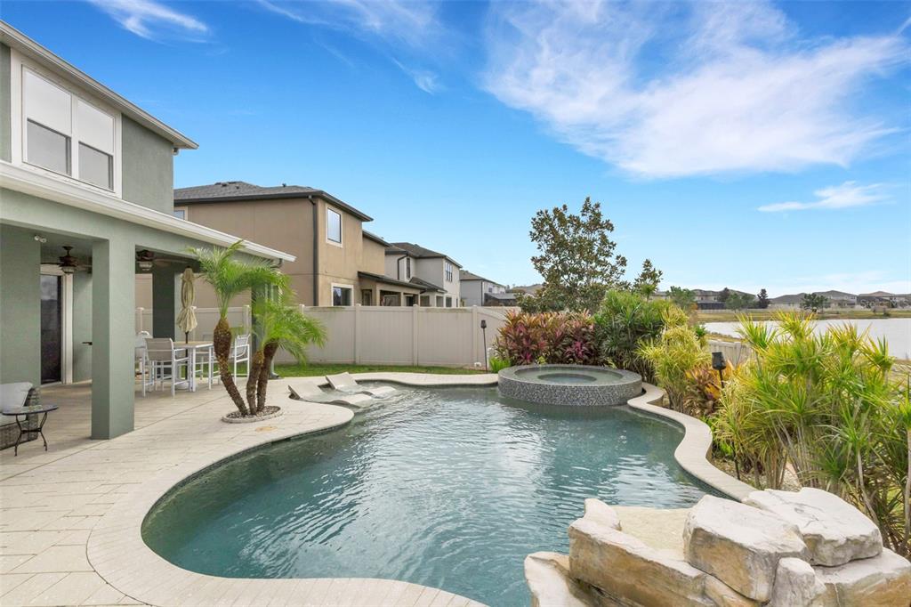 A backyard swimming pool with a spa, tanning ledge, and patio at sunset — 19613 LONG LAKE RANCH BOULEVARD, LUTZ, FL