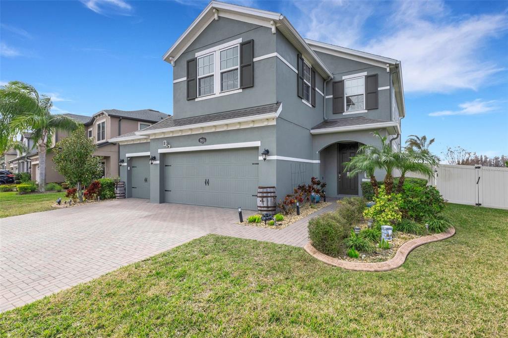 An aerial view shows a two-story green house with a paved driveway facing a lake — 19613 LONG LAKE RANCH BOULEVARD, LUTZ, FL