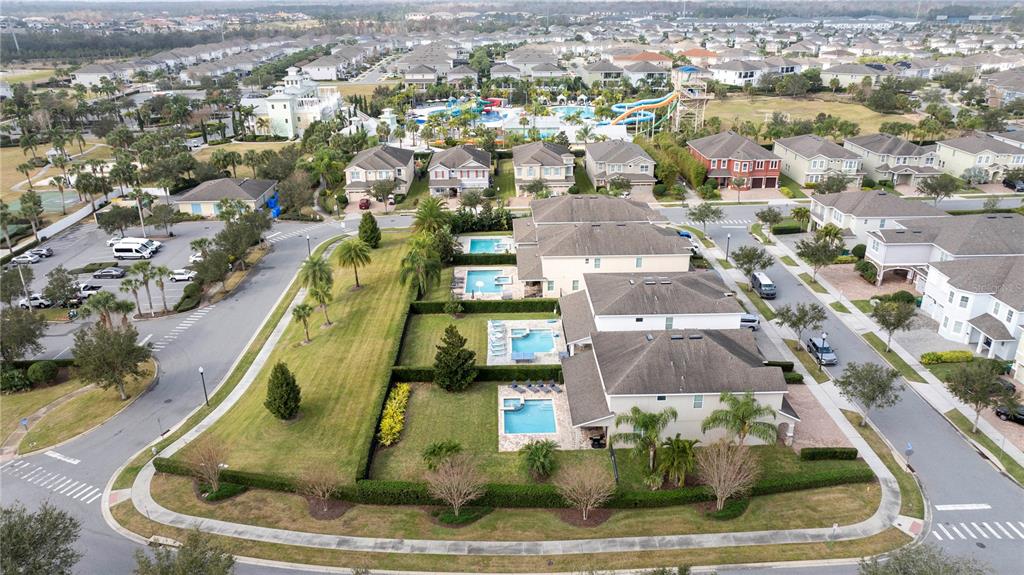 An aerial view shows residential houses with private pools and a nearby community water park — 7600 MACKINAW LANE, KISSIMMEE, FL