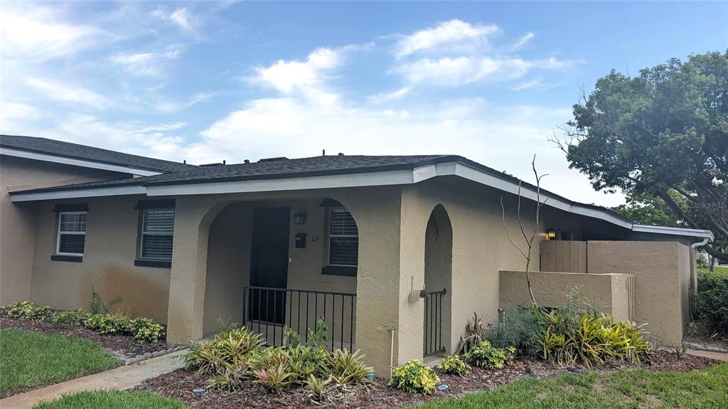 A tan, single-story residential building features a covered entryway with a black metal railing — 519 POLARIS LOOP UNIT 109, CASSELBERRY, FL