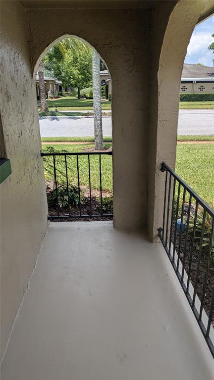 A covered concrete porch features arched openings and black metal railings overlooking a grassy yard — 519 POLARIS LOOP UNIT 109, CASSELBERRY, FL