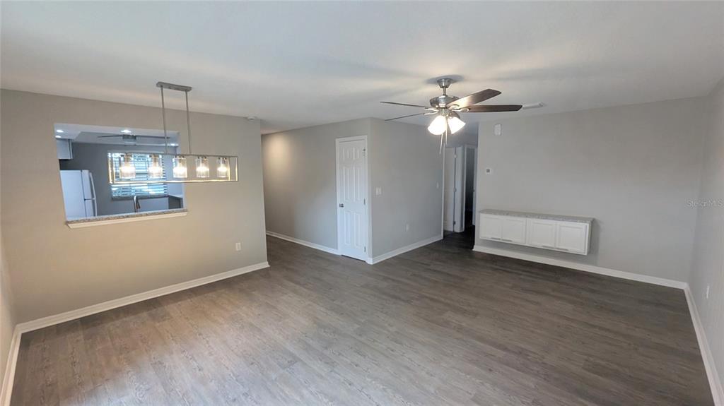 A living and dining area features gray walls, wood-look flooring, a ceiling fan, and pendant lighting — 519 POLARIS LOOP UNIT 109, CASSELBERRY, FL
