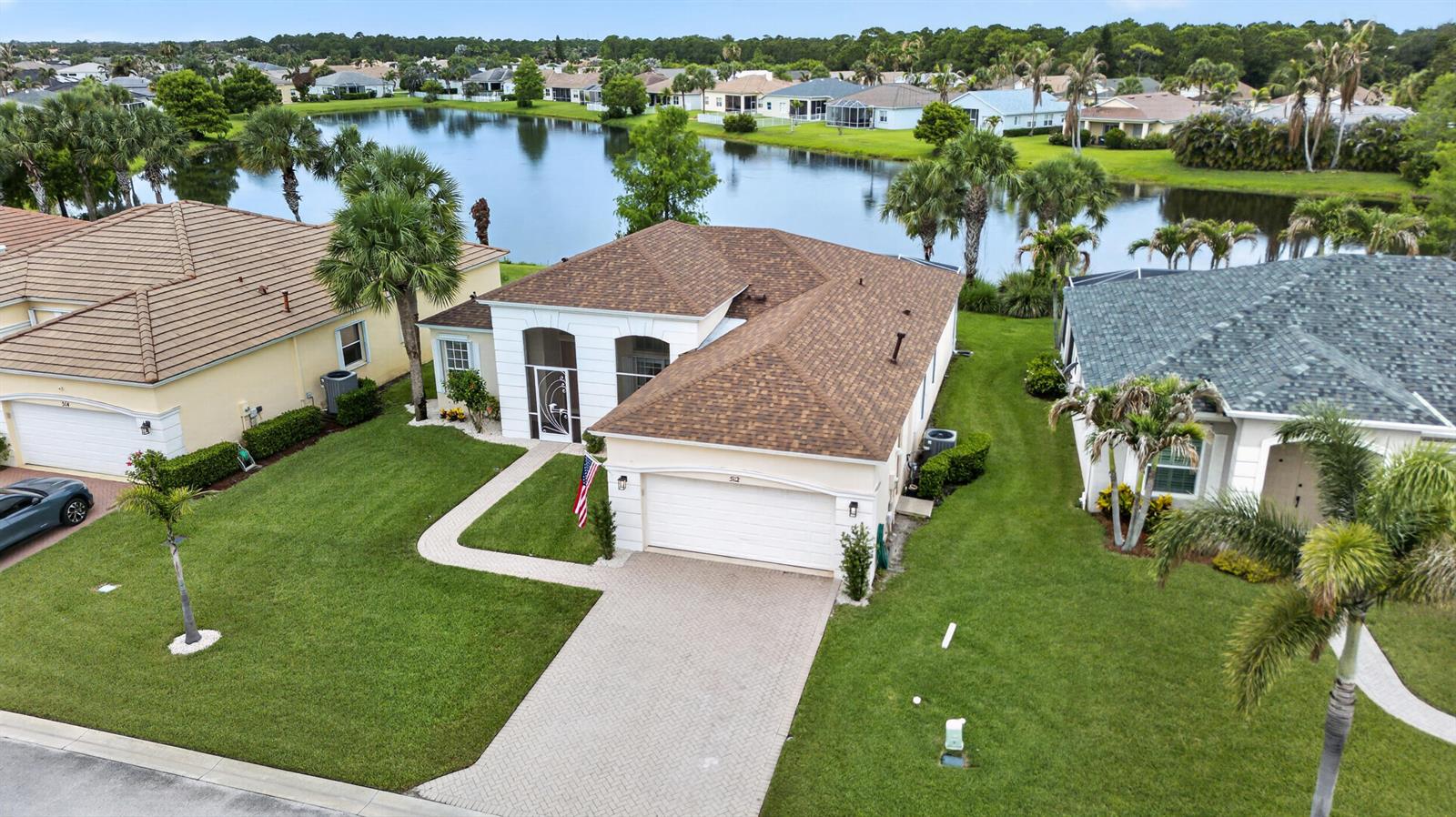 An aerial view shows a single-story house with a brown roof and a paved driveway — 512 SW Lake Manatee Way, FL 34986, FL