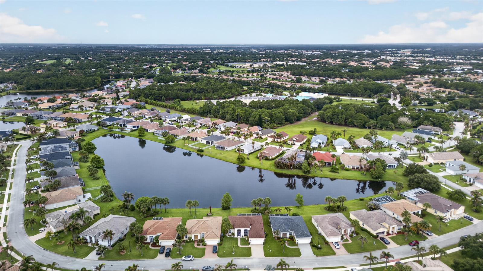 An aerial view shows a residential neighborhood with houses surrounding a large, central lake — 512 SW Lake Manatee Way, FL 34986, FL