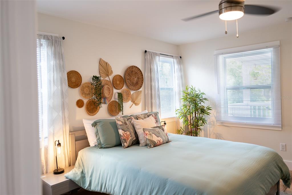 A bedroom features a bed with light blue bedding, a wall gallery of woven baskets, and windows — 127 17TH AVENUE S, ST PETERSBURG, FL