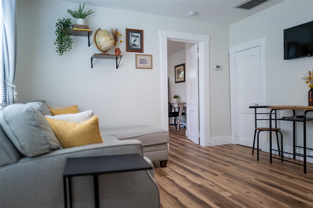 A living room features a grey sectional sofa, wood-look flooring, and a small dining area — 127 17TH AVENUE S, ST PETERSBURG, FL