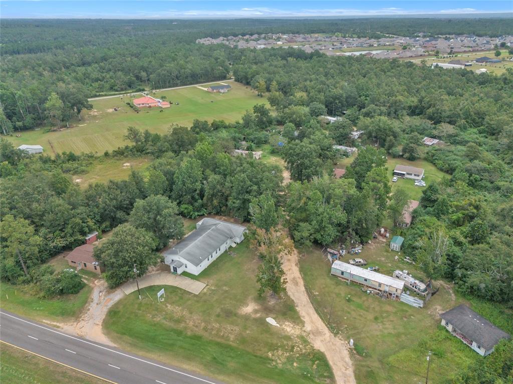 An aerial view shows a white building, a mobile home, and several houses near a road — 465 HAZZARD LANE, CANTONMENT, FL