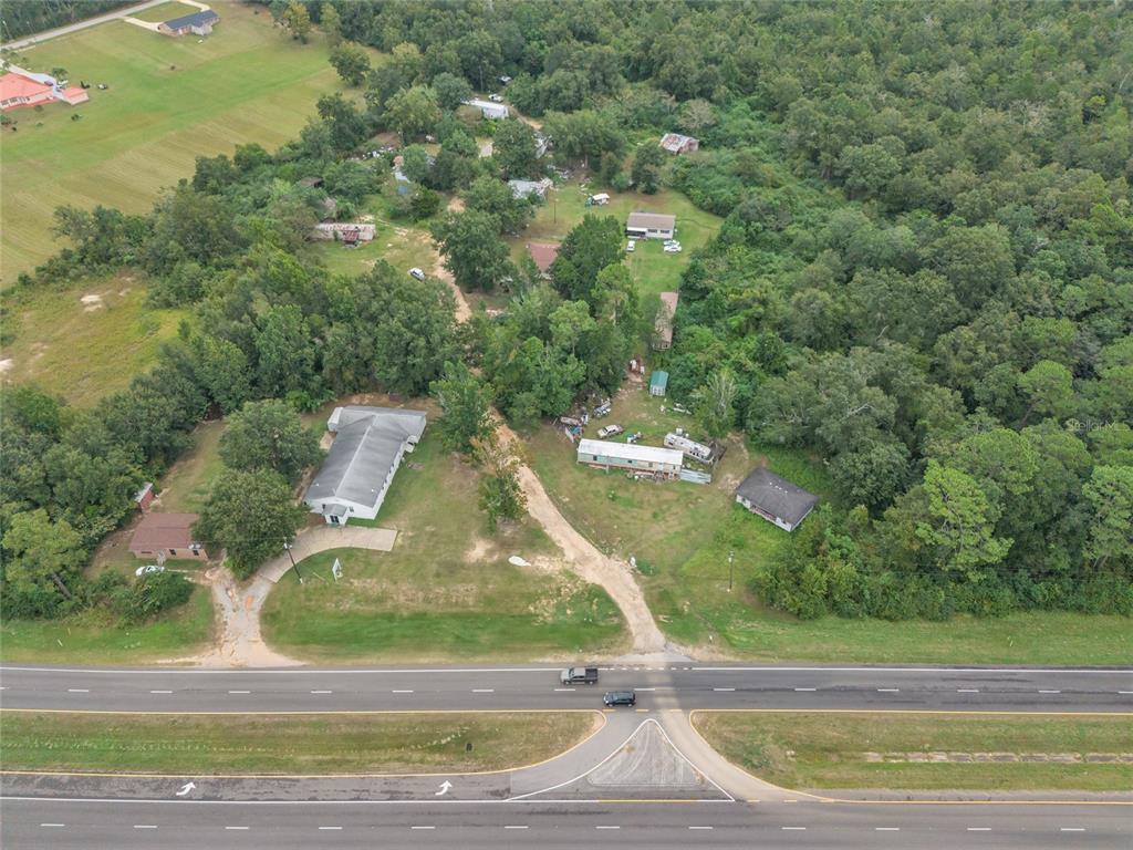 An aerial view shows several buildings and mobile homes situated on a wooded rural lot — 465 HAZZARD LANE, CANTONMENT, FL