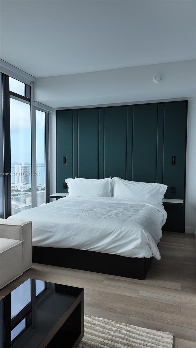 A bedroom features a dark green paneled headboard, a white bed, and floor-to-ceiling windows — 20 NE 11th St # 1505, Miami FL 33132, MIAMI, FL