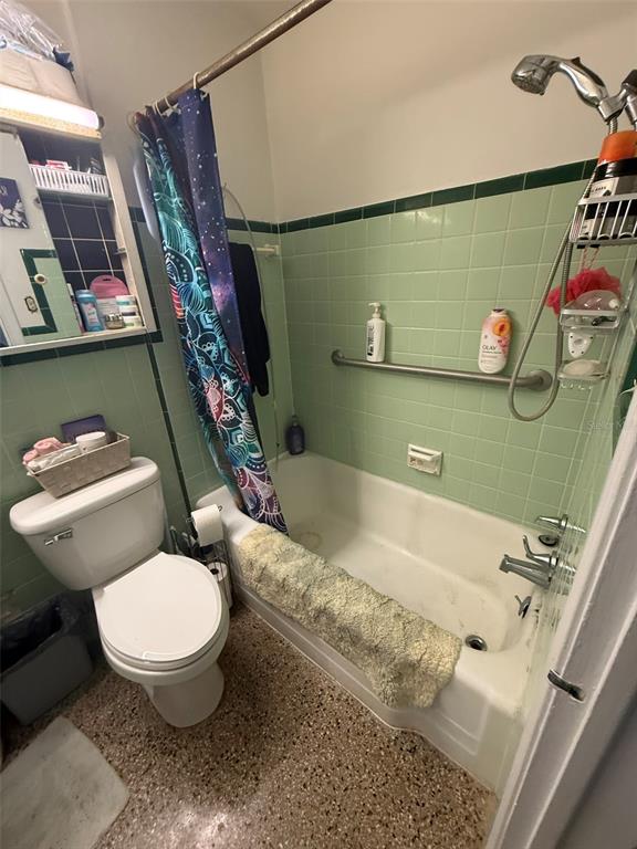 A bathroom features a toilet, a bathtub with a showerhead, and green tiled walls — 316 76TH AVENUE, ST PETE BEACH, FL