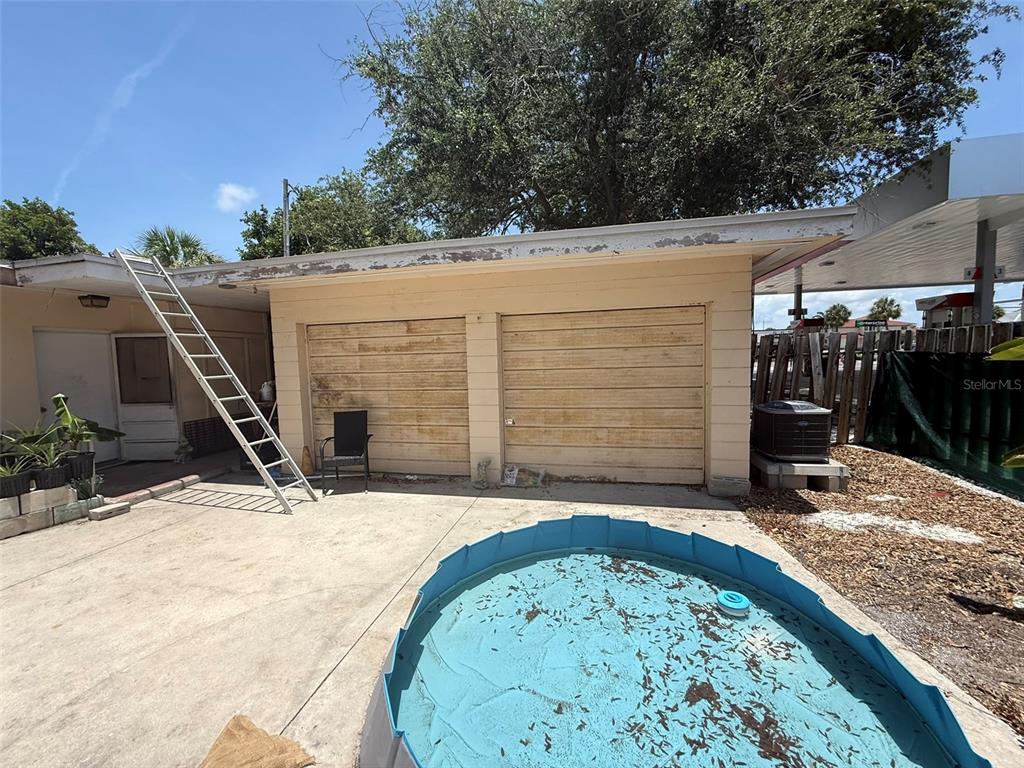 A detached garage with a ladder leaning against the roof sits beside a small pool — 316 76TH AVENUE, ST PETE BEACH, FL
