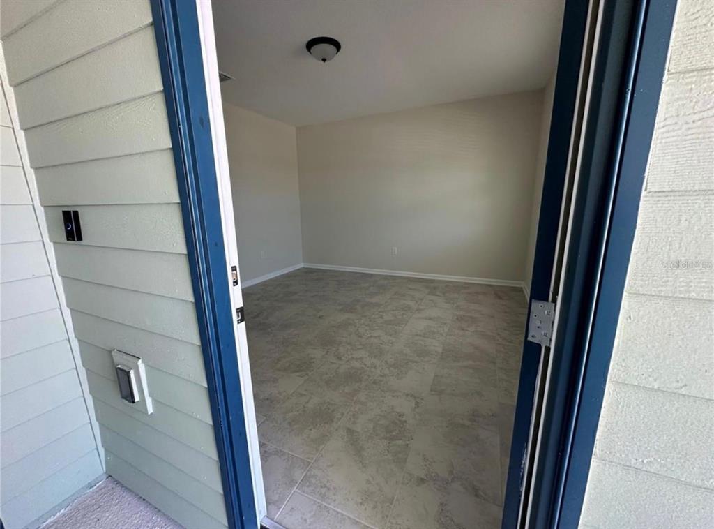 A view through an open doorway into an empty room with light-colored tile flooring — 4500 BLUFF OAK LOOP UNIT 1, KISSIMMEE, FL