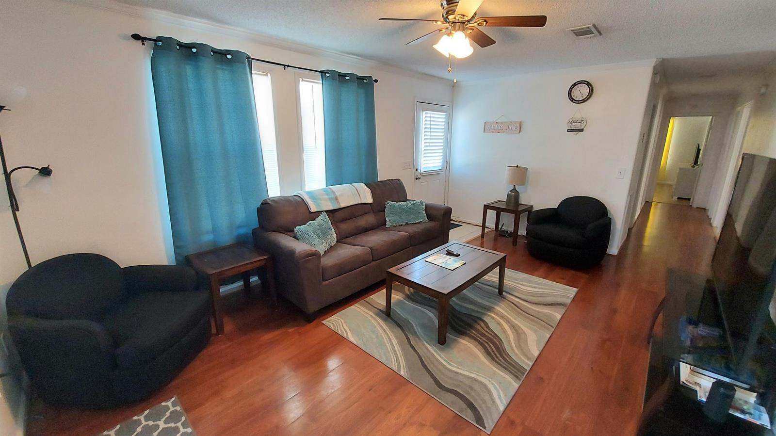 A living room features a brown sofa, two black armchairs, a coffee table, and hardwood floors — 1401 W 9th Street, Riviera Beach FL 33404, RIVIERA BEACH, FL