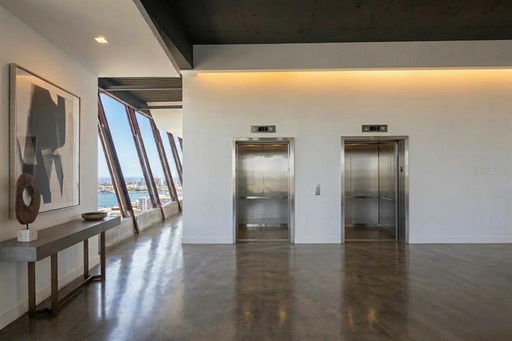 A modern elevator lobby with polished concrete floors, white walls, and floor-to-ceiling angled windows — 602 MANUEL FERNÁNDEZ JUNCOS AVENUE UNIT 27, SAN JUAN, PR