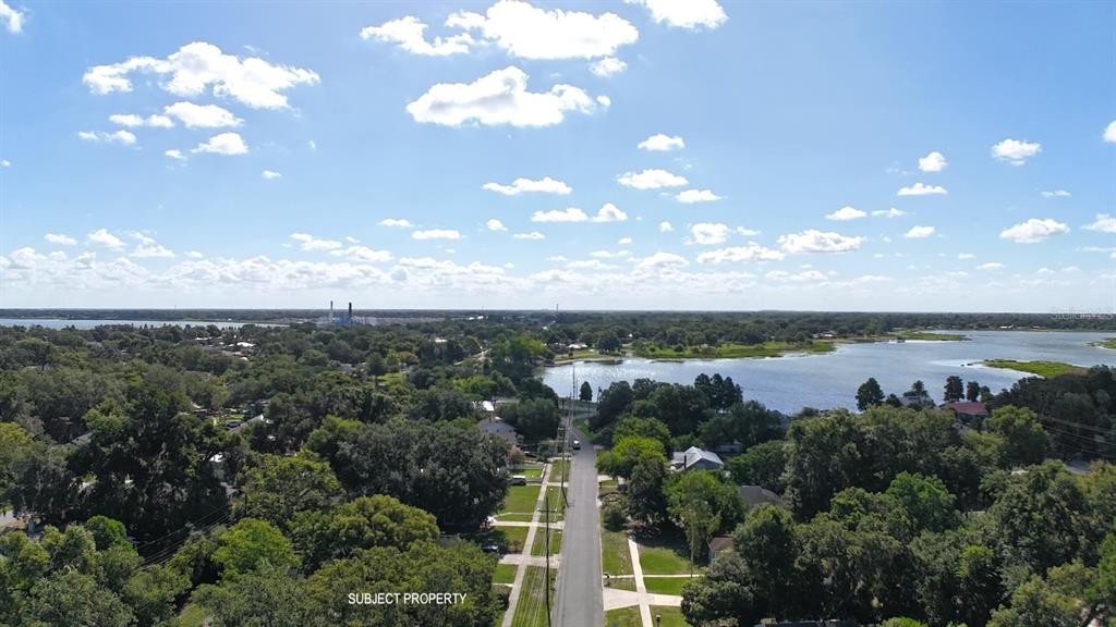 An aerial view shows a residential street leading toward a lake under a cloudy sky — 1410 ELGIN STREET, LAKELAND, FL