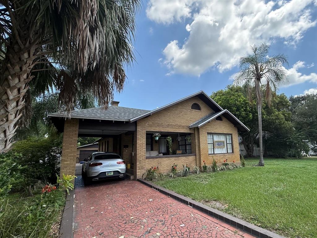 A single-story brick house features a covered carport, a front porch, and a paved driveway — 1410 ELGIN STREET, LAKELAND, FL