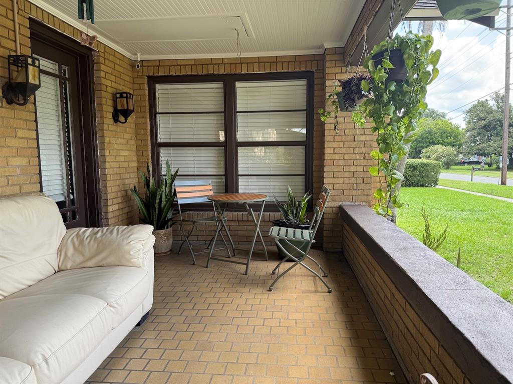 A covered brick porch features a white sofa, a small bistro set, and hanging plants — 1410 ELGIN STREET, LAKELAND, FL