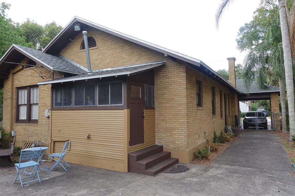 A side view of a tan brick house with a covered carport and concrete driveway — 1410 ELGIN STREET, LAKELAND, FL