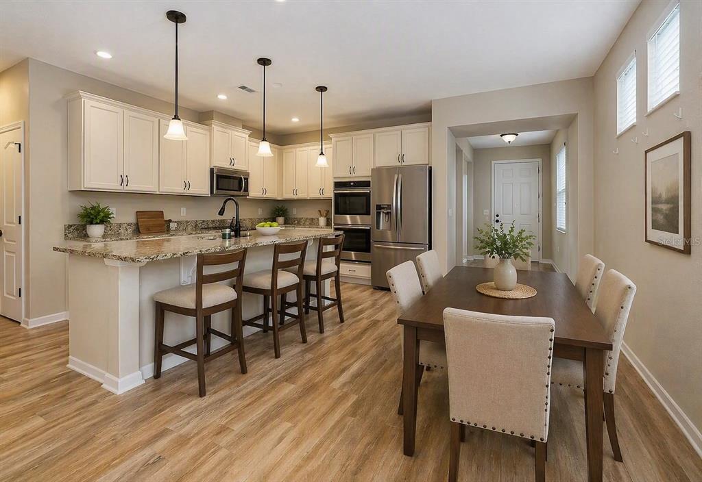 A kitchen with white cabinets, granite countertops, and an island with stools near a dining area — 15403 MURCOTT HARVEST LOOP, WINTER GARDEN, FL
