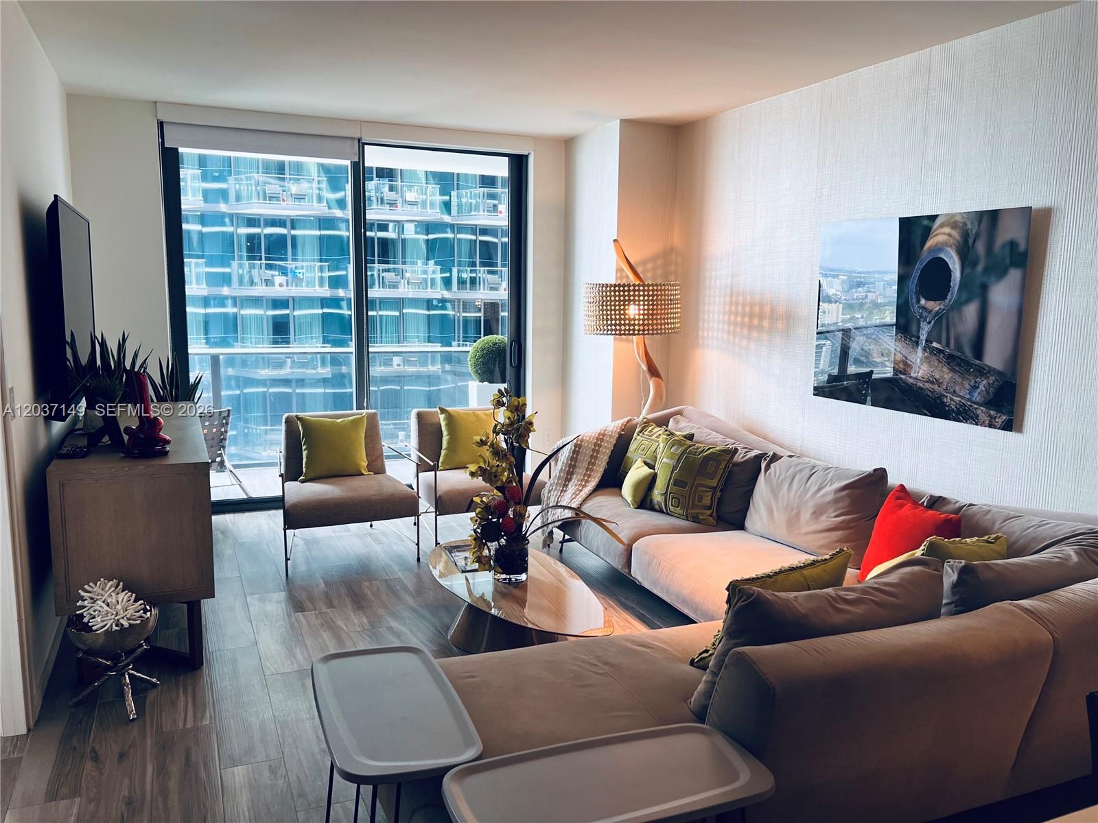 A modern living room features a sectional sofa, two armchairs, and floor-to-ceiling windows — 801 S Miami Ave # 3608, Miami FL 33130, MIAMI, FL