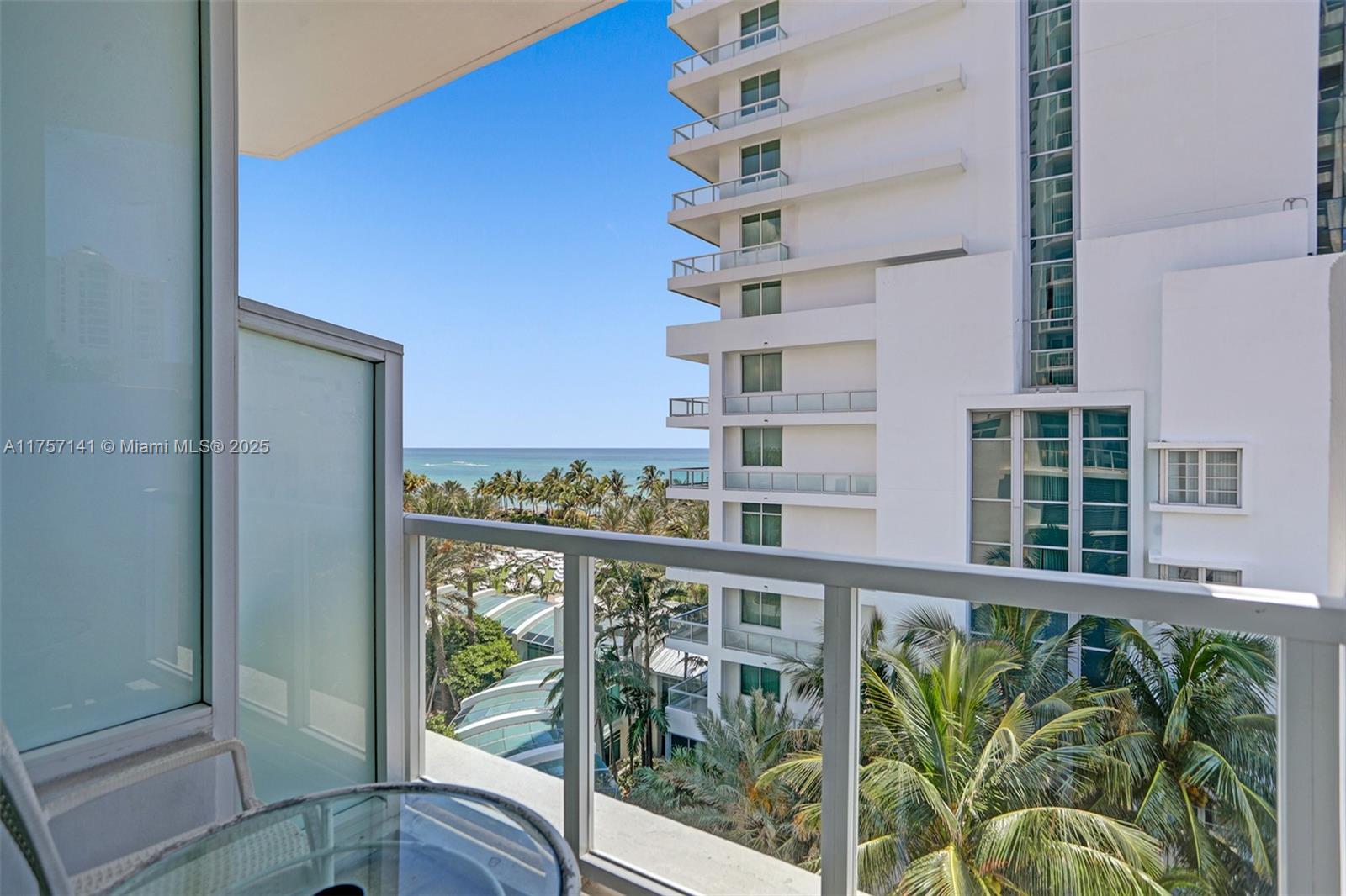 A balcony view overlooks palm trees, a neighboring high-rise building, and the ocean — 4401 Collins Ave, Miami Beach FL 33140, MIAMI BEACH, FL