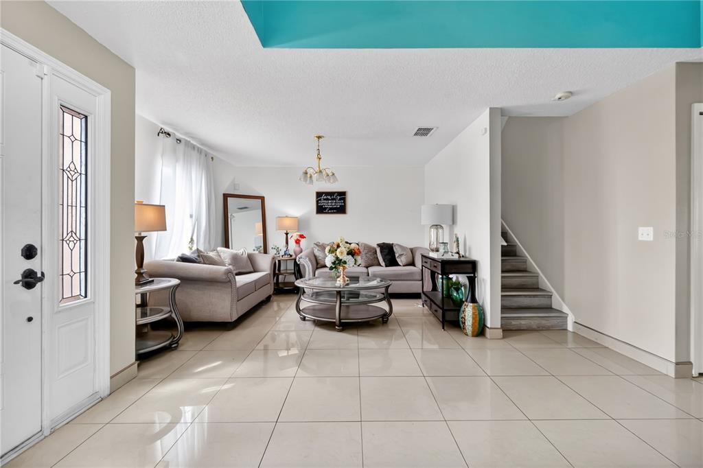 A living room features light tile flooring, a staircase, and two grey sofas — 1945 MYAKKA COURT, KISSIMMEE, FL