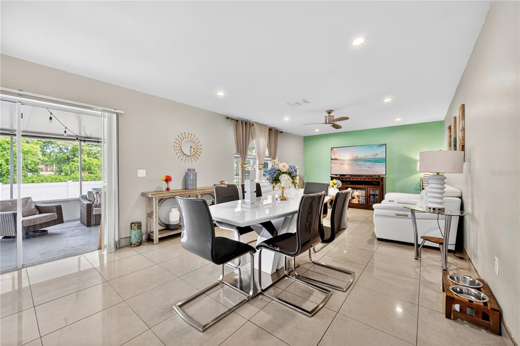 A dining area with a white table, black chairs, and a green accent wall — 1945 MYAKKA COURT, KISSIMMEE, FL